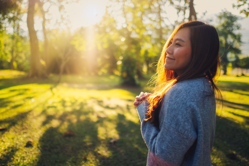 Portrait-image-of-a-beautiful-asian-woman-standing-among-nature-in-the-park-before-sunset